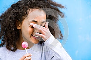 African american girl with curly hair outdoors eating lollipop.