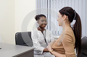 An African-American girl Doctor listens, examines a patient with a stethoscope in her office at the hospital.