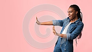 African American Girl Gesturing Stop Looking Aside On Pink Background photo