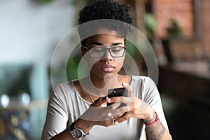 African American girl in glasses using cellphone chatting