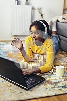 African American girl in headphones watching the video lesson on computer, happy child in earphones have online