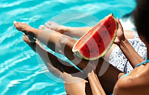 African American girl with her best friend eating watermelon near swimming pool, closeup