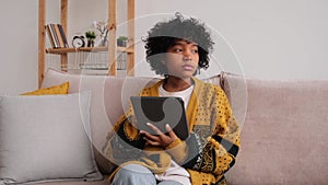 African American girl holding digital tablet touch screen typing scroll page at home. Woman with mobile tech device