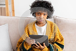 African american girl holding digital tablet touch screen typing scroll page at home. Woman with mobile tech device