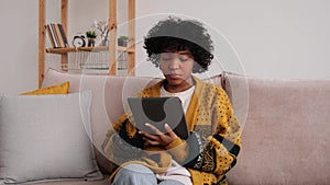 African American girl holding digital tablet touch screen typing scroll page at home. Woman with mobile tech device