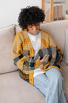 African american girl holding digital tablet touch screen typing scroll page at home. Woman with mobile tech device