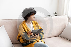 African american girl holding digital tablet touch screen typing scroll page at home. Woman with mobile tech device