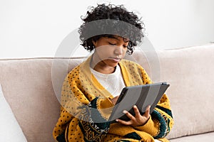 African american girl holding digital tablet touch screen typing scroll page at home. Woman with mobile tech device