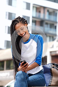 African american girl reading text message on mobile phone outdoors