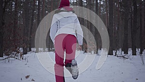 African american girl running through winter forest. Beautiful girl in warm jacket turns and looksaround, she is scared