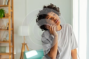 African american girl talking on smartphone at home indoor. Young woman with cell phone chatting with friends. Smiling