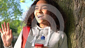 African American girl teenager leaning against a tree using cell phone