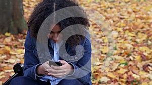African American girl teenager young teen outside happy and smiling using her cell phone for social media
