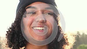 African American girl teenager young woman wearing a black beanie hat laughing backlit by the sun in evening sunshine