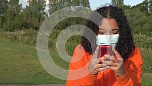 African American girl teenager young woman wearing a face mask during COVID-19 Coronavirus pandemic using her cell p