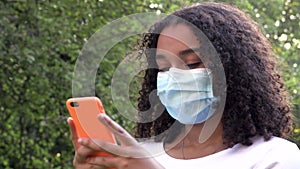 African American girl teenager young woman wearing a face mask during COVID-19 Coronavirus pandemic using her smartphone