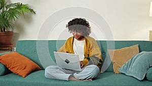 African american girl using laptop at home office looking at screen typing chatting reading writing email. Young woman