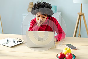 African american girl using laptop at home office looking at screen typing chatting reading writing email. Young woman