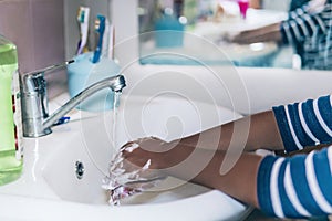 African-American girl washes hands. Cropped image of person washing hands at sink in bathroom, Coronavirus hand washing