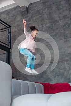 African-American girl wearing jeans staying on sofa at home