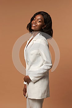 Girl in white suit posing on beige background