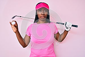 African american golfer woman with braids holding golf ball depressed and worry for distress, crying angry and afraid