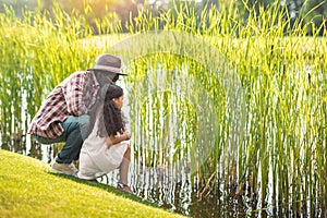 african american granddaughter and her grandfather sitting near lake