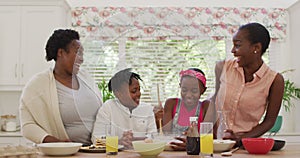 African american grandmother, mother and kids preparing dinner in the kitchen at home