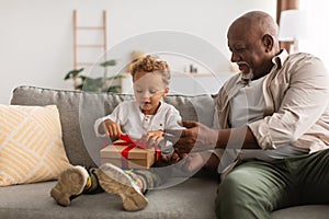 African American Grandpa Giving Wrapped Gift To Grandson At Home