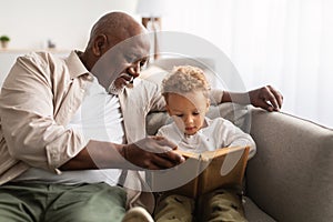 African American Grandpa And Grandson Reading Book Together At Home