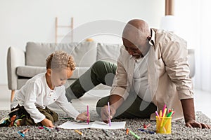 African American Grandpa And Grandson Sketching Sitting On Floor Indoors