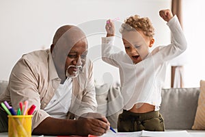 African American Grandpa And Grandson Sketching Together At Home