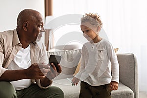 African American Grandpa And Grandson Using Phone Sitting At Home