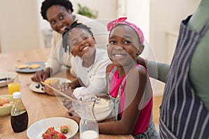 African american grandparents cooking with smiling grandson and granddaughter in kitchen