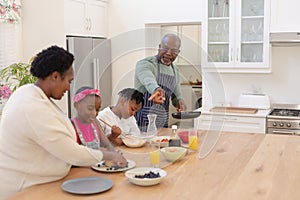 African american grandparents cooking with smiling grandson and granddaughter in kitchen