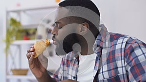 African american guy biting croissant and feeling toothpain, gum sensitivity