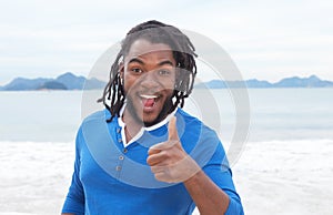 African american guy with dreadlocks at beach showing thumb up