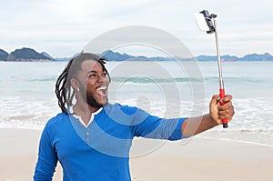 African american guy with dreadlocks taking selfie at beach