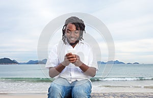 African american guy with dreadlocks and white shirt typing message