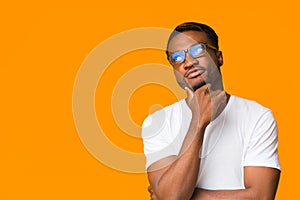 African American Guy Thinking Touching Chin Standing Over Orange Background