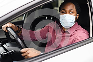 African-American guy wearing protective mask driving a car