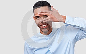 African American handsome young man hiding his face with palm and show his eye.