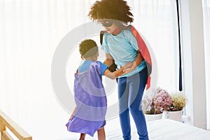 African American happy and confident young kids playing and dressing up as superhero together in bedroom