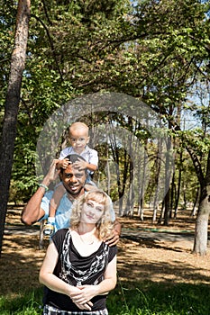 African American happy family: black father, mom and baby boy on nature