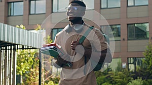 African American happy smiling student guy ethnic university man male with backpack school bag and books smile walking