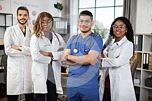 African American, Indian and Arabian medical students posing at camera in modern conference room