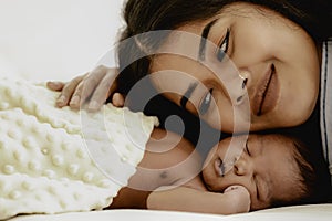 African american infant baby lying on bed with mother watching beside