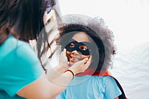 African American kid being supported and helped by supportive mother for little adventure and protection.