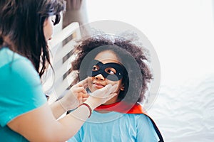 African American kid being supported and helped by supportive mother for little adventure and protection.