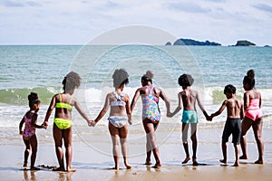 African American, Kids group in swimwear enjoying running to play the waves on beach. Ethnically diverse concept. Having fun after